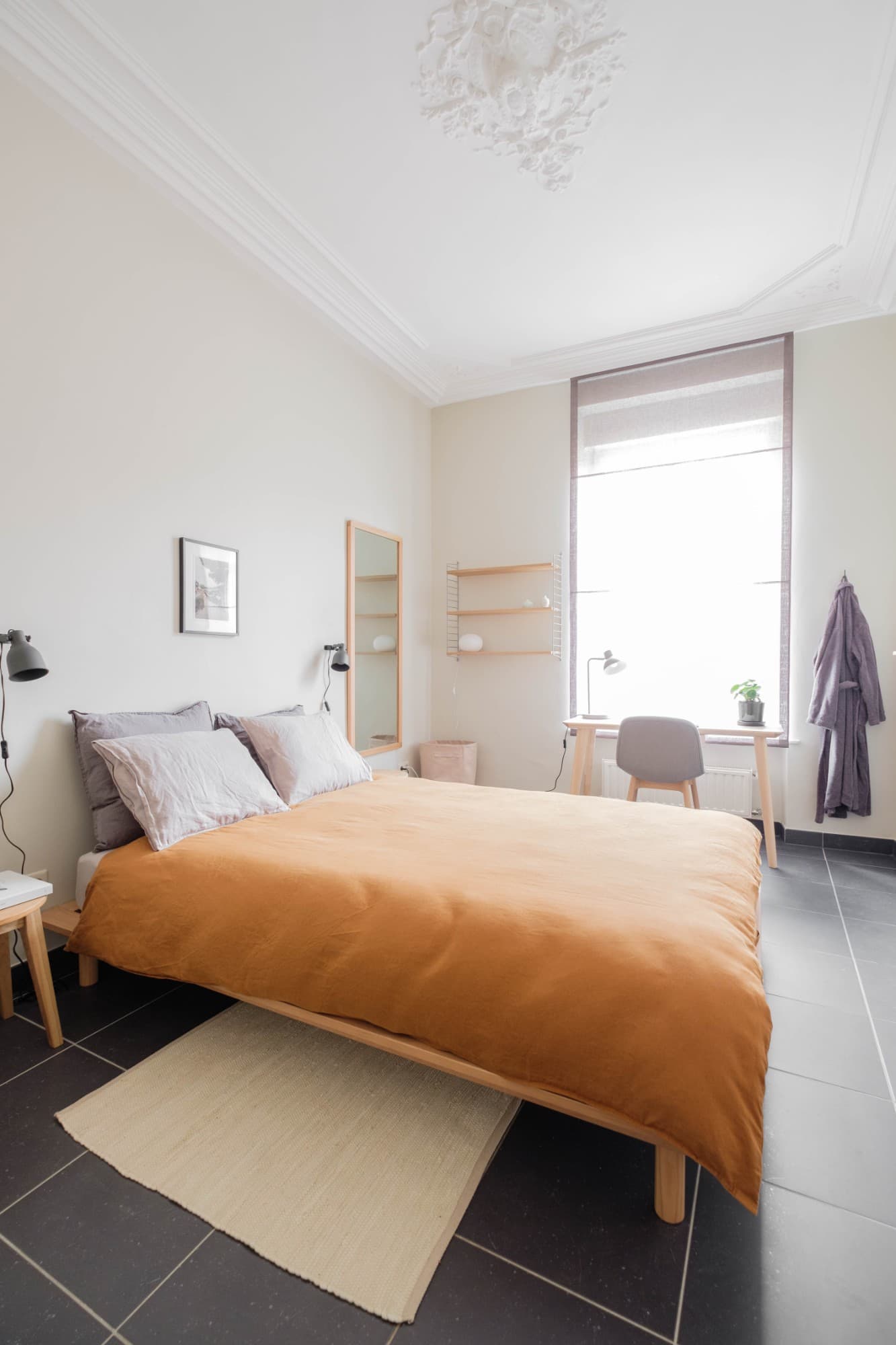 A room at the Orchard 13 flatshare in Luxembourg-Bonnevoie: terracotta linen, pale wood, a ceiling rose